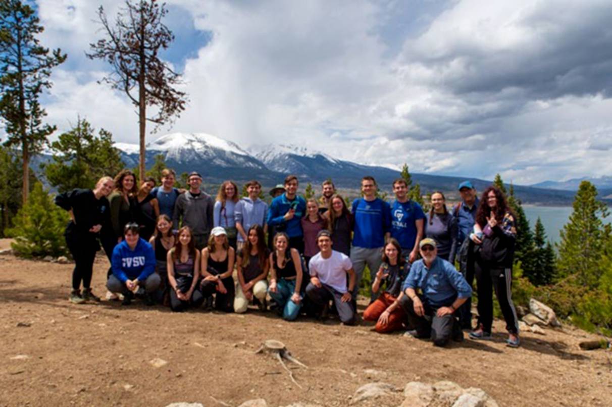 a group photo in front of a large snow capped mountain